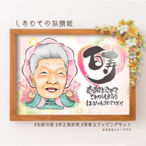 ピンクの祝着を着た似顔絵、百寿の筆文字、「感謝を込めてこれからも元気なばあちゃんでいてください」のメッセージ。